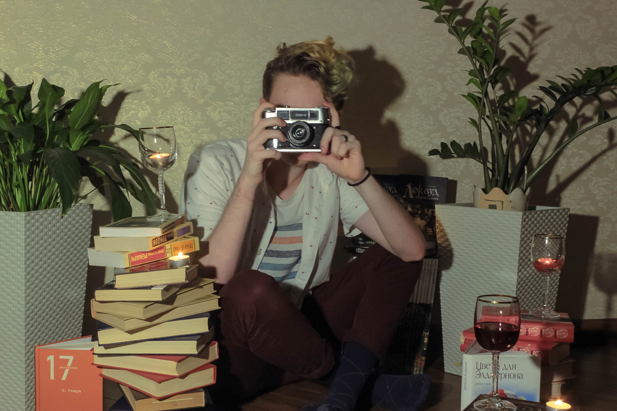 man taking photo surrounded by books