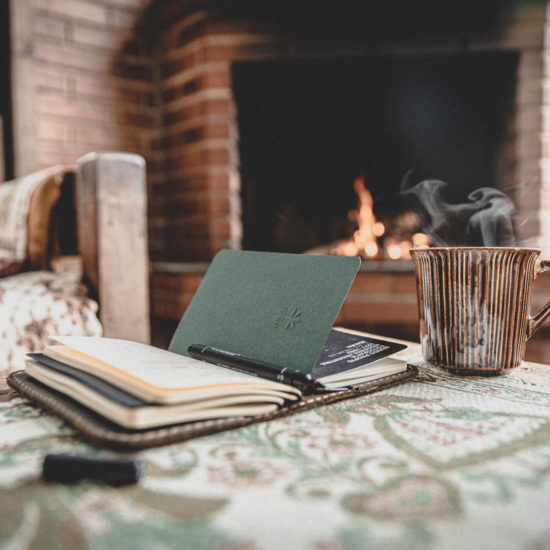 notebook and coffee mug by the fireplace