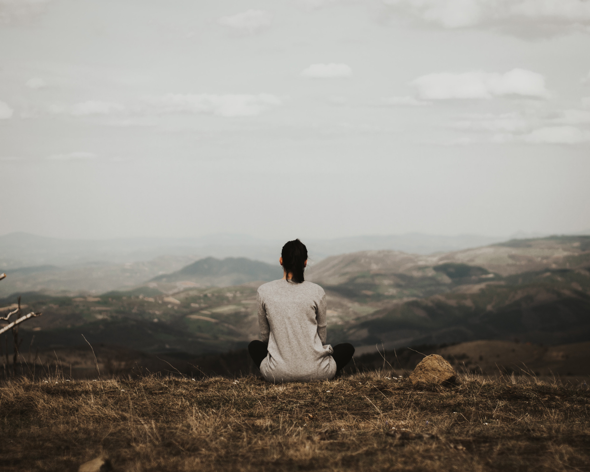woman sitting on mountaintop