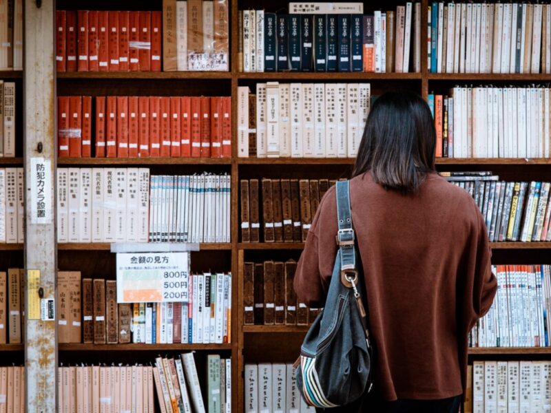 person standing in front of bookshelf at library
