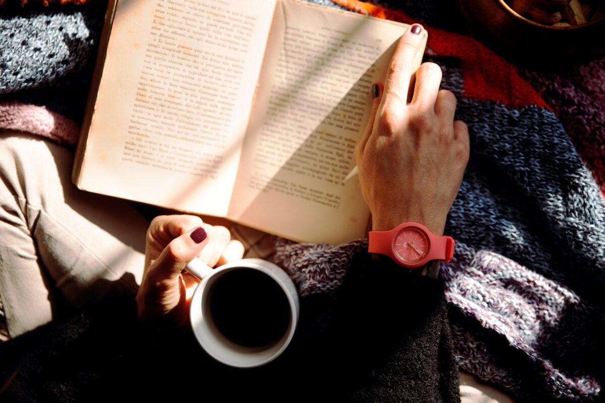 person with a cup of coffee and a book
